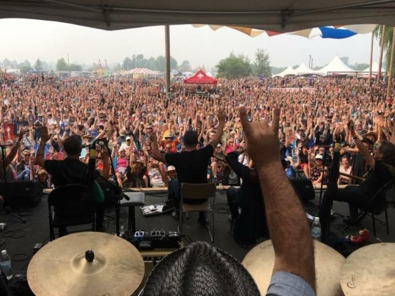 Photo with a hand mimicking the devils horn sign during a crowded concert event.