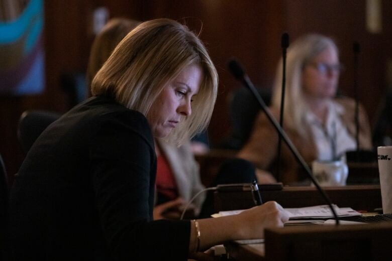 Vancouver City Councillor Rebecca Bligh, with A Better City, writes on paper at a council meeting.