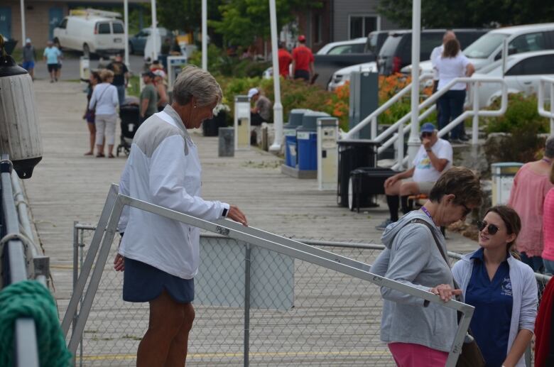 Some ladies walk down a boat ramp onto a dock 