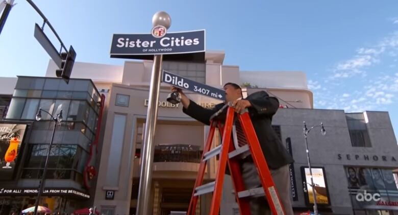 Man on ladder installing a sign.