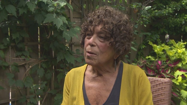 A close up of a woman sitting in her garden.