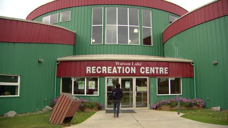 An entranceway to a large green building, seen from the outside. 