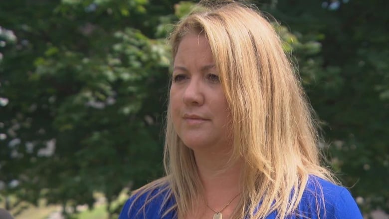 A woman gives an interview outside on a warm sunny day.