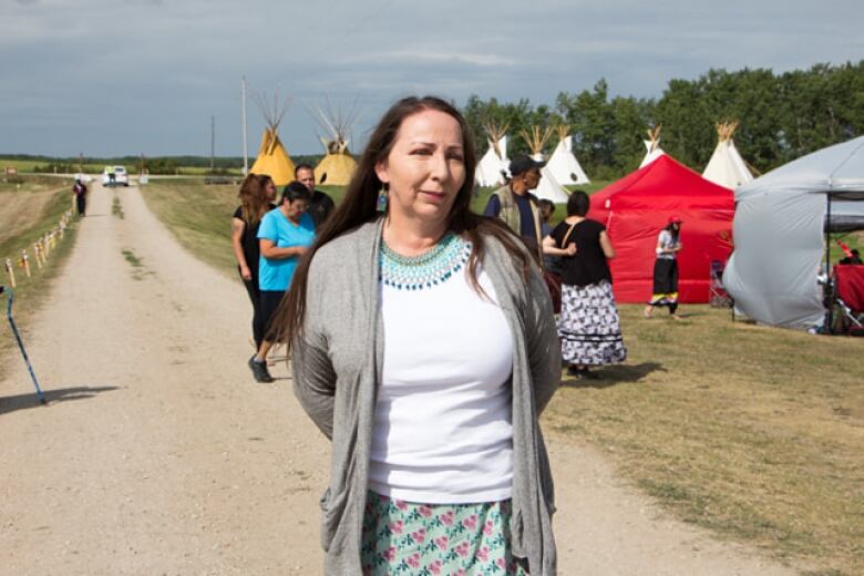 A woman standing in front of a field with teepees.