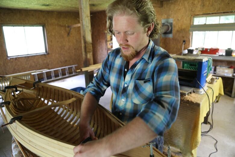 A man building a canoe in a workshop.