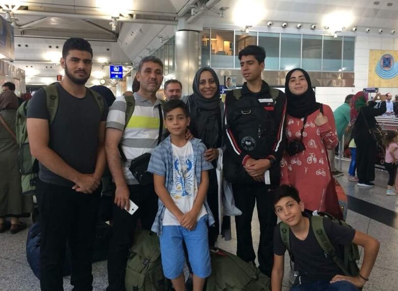 A family of seven standing together in an airport. 