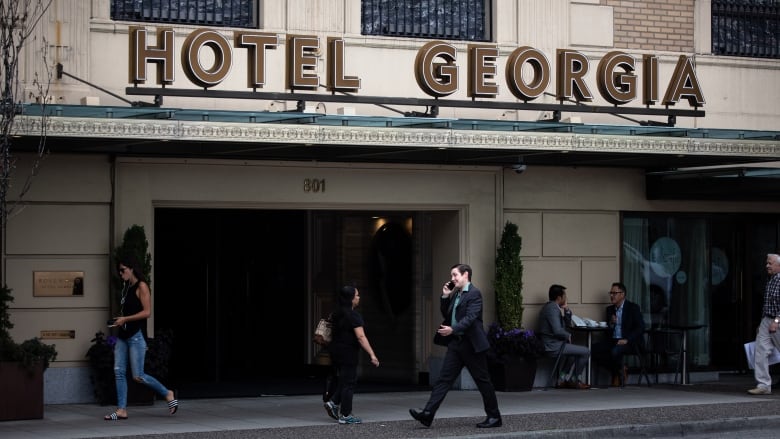 Pedestrians walk in front of Hotel Georgia in Vancouver.