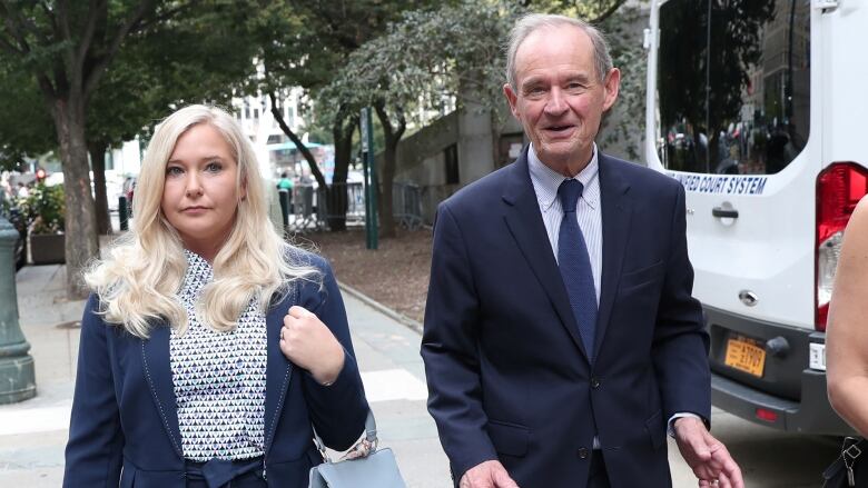 A woman carrying a purse walks with a man down a street.