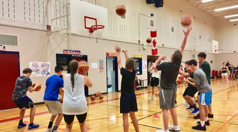 Children take turns shooting a basketball at a net.