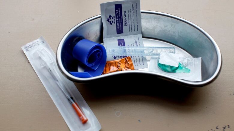 A kit at an overdose prevention site including a needle in a sealed package, swabs and a rubber band.