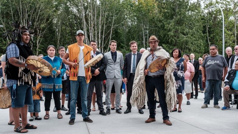 A group of Indigenous people stand with government officials and school staff.