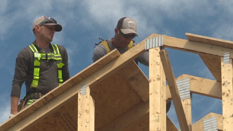 Two construction workers building a roof.