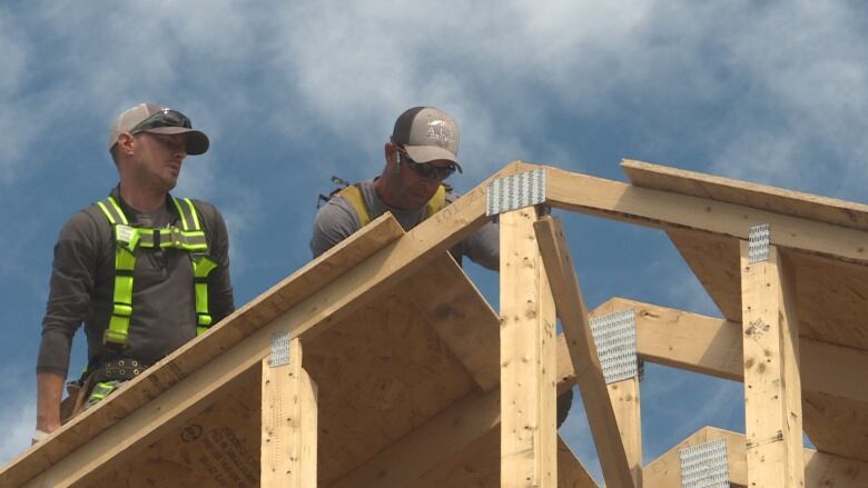 Two construction workers building a roof.