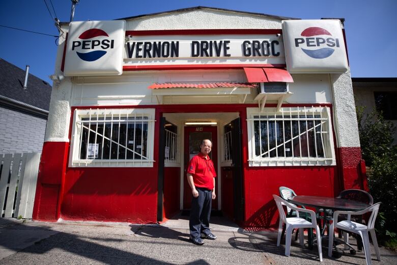 A retro storefront that says Vernon Drive Grocery, with an older Chinese man standing outside. 