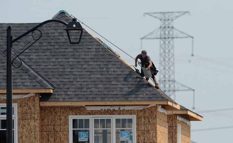 A man puts shingles on a roof.