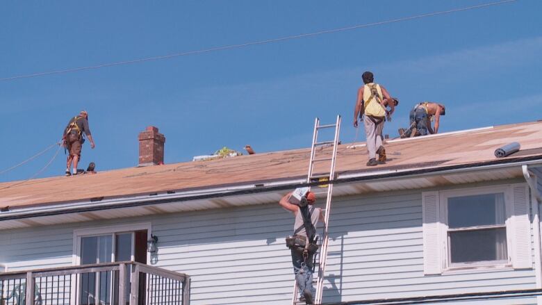 Five men work on the roof of a house.