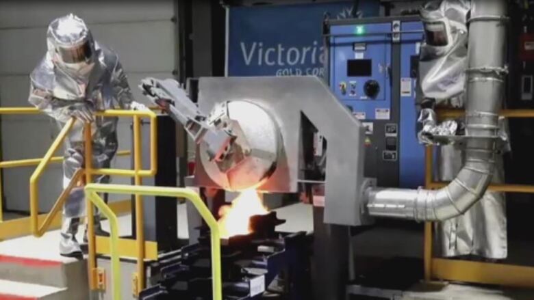 A person in a silver protective suit works inside an industrial facility.