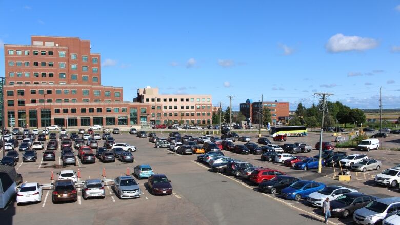 A red brick building in the background with dozens of vehicles parked in the foreground.