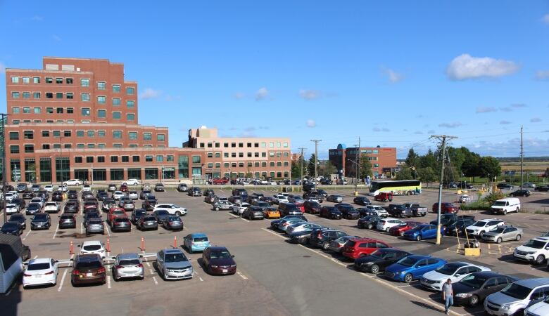 A red brick building in the background with dozens of vehicles parked in the foreground.