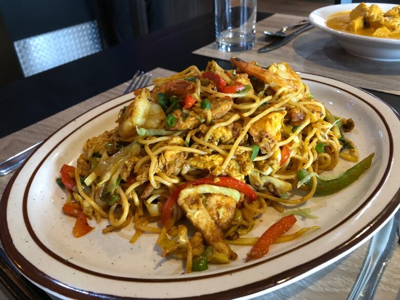 A plate of noodles, chicken and mixed vegetables.