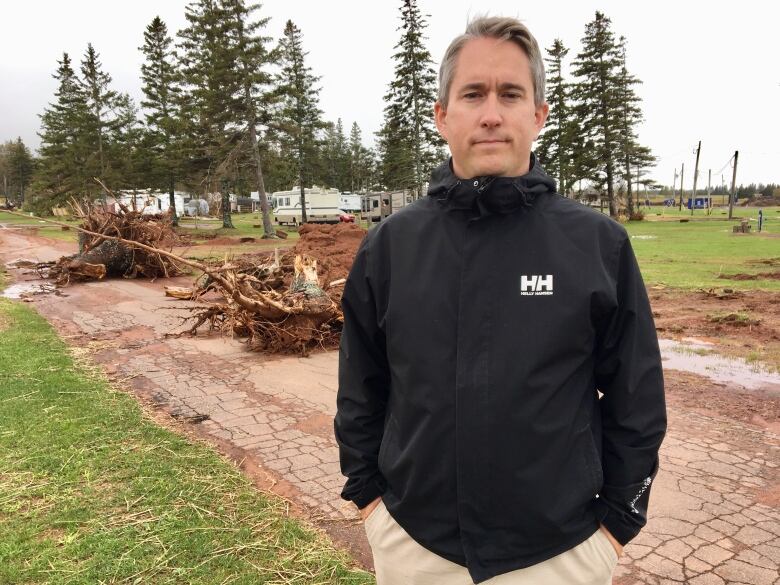 Matthew Wedge stands on his campground, downed trees seen behind him after post-tropical storm Dorian in 2019. 