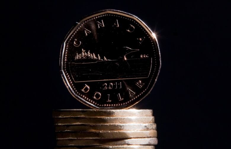 A Canadian loonie sits atop a small pile of coins.