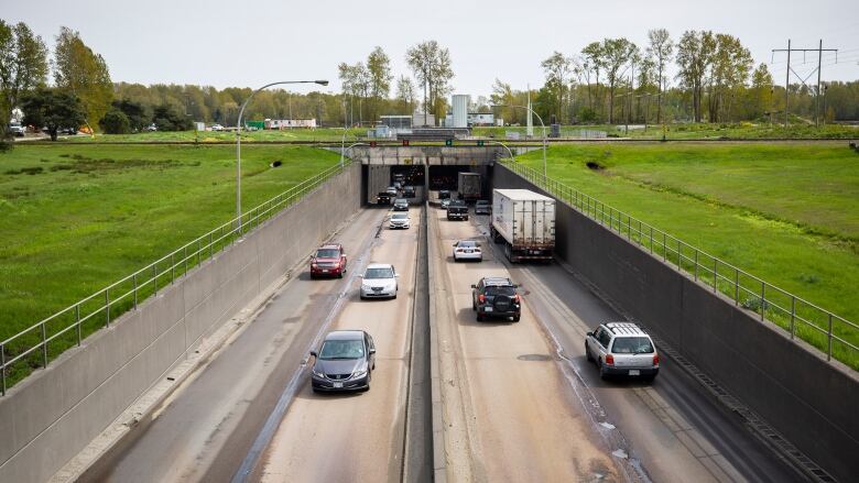 An underpass tunnel with cars driving through is pictured on a sunny day. 