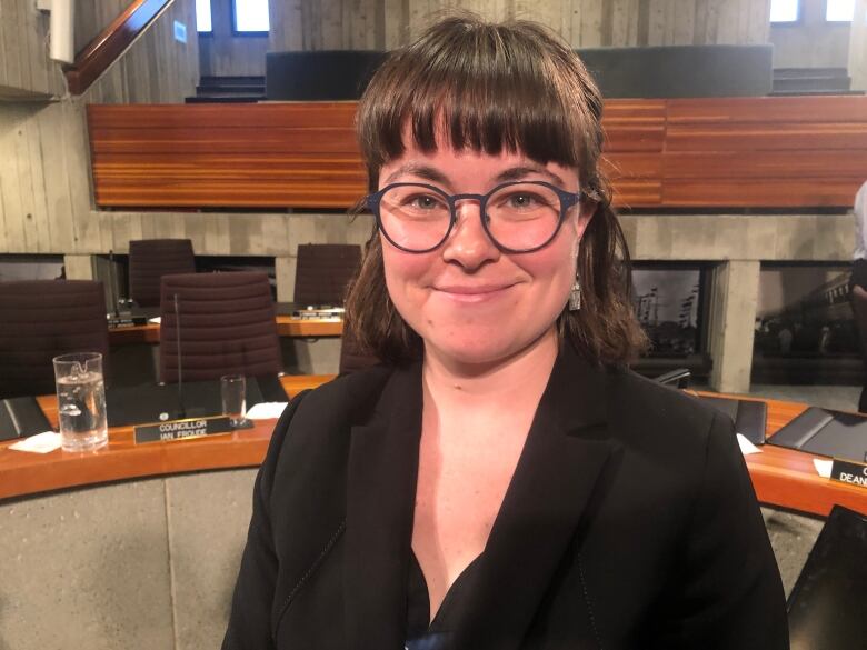 A smiling woman with bangs and glasses.