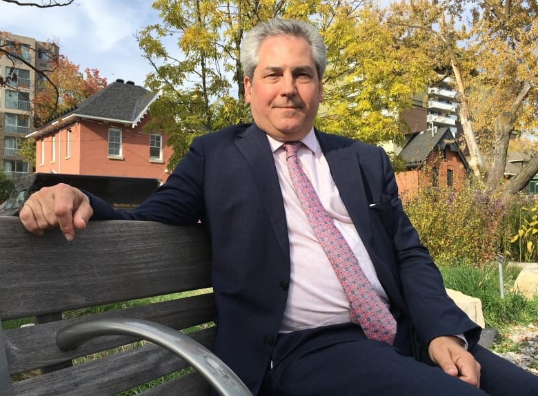 A man sits on a bench in a suit.