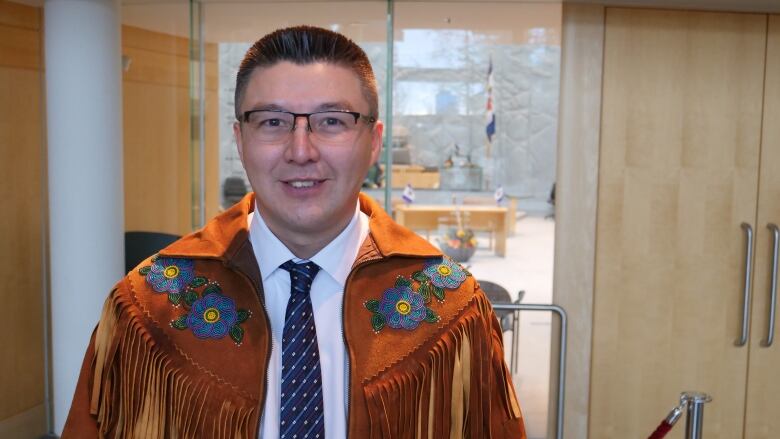 A man wearing regalia poses for a photo in the Legislative Asssembly