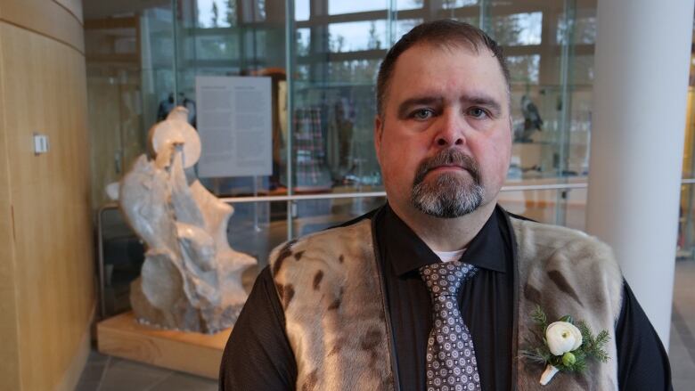 Photo of MLA Jackie Jacobson in the NWT Legislative Assembly standing in front of a carving. 