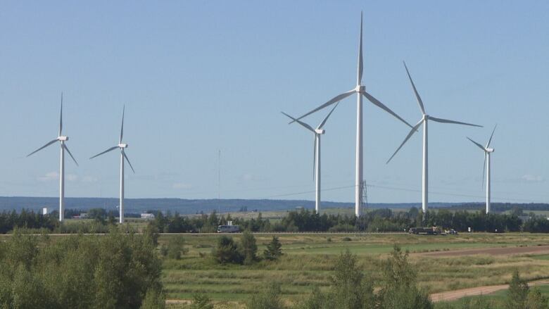 Wind turbines stand in a sunlit landscape.