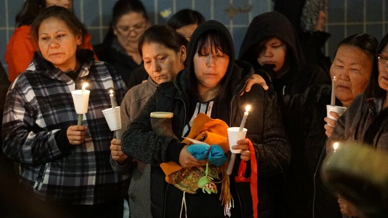 A group of women hold candles.