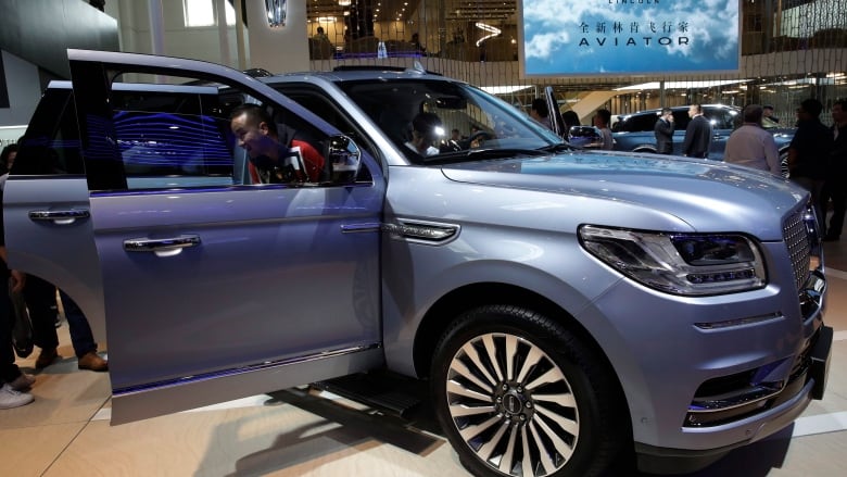 A blue SUV with its doors open is on display at an auto show