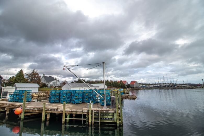 A fishing dock with lobster traps on it, below cloudy skies.