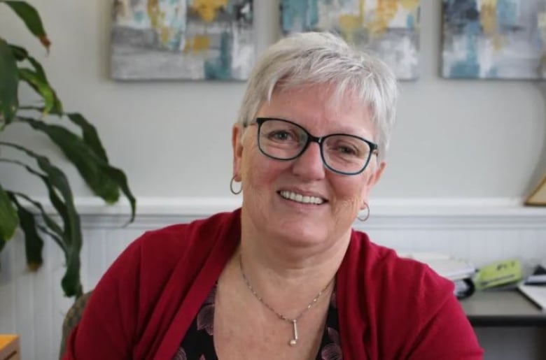 A woman in a red top and black glasses