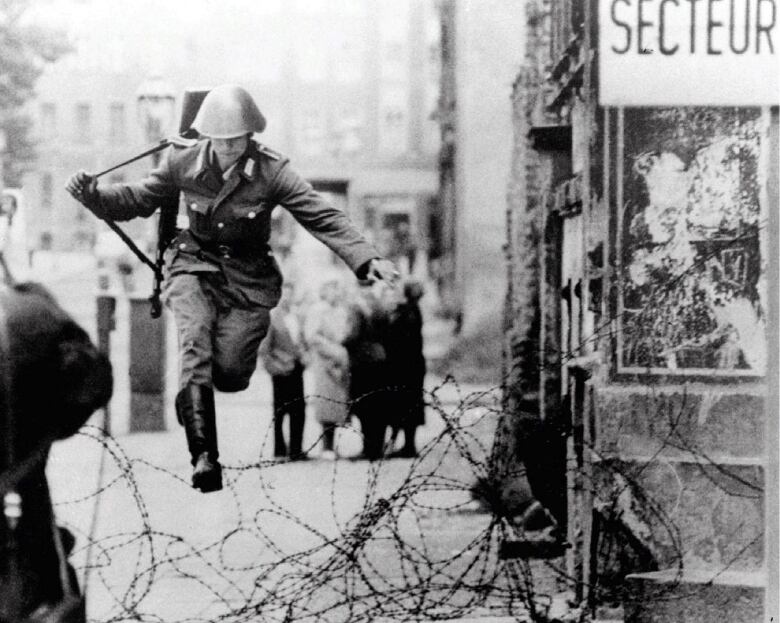 Soldier jumps over tangle of barbed wire on a street