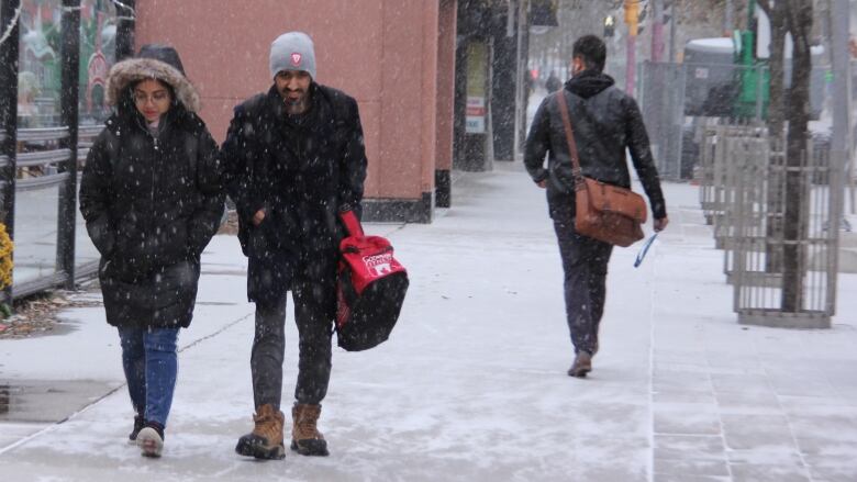 Two people walk towards the camera on sidewalk in downtown core