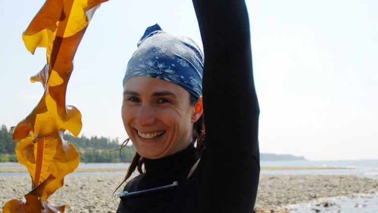 A woman holds up a piece of kelp