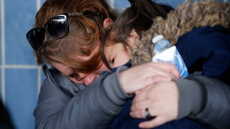 Tearful women hug.