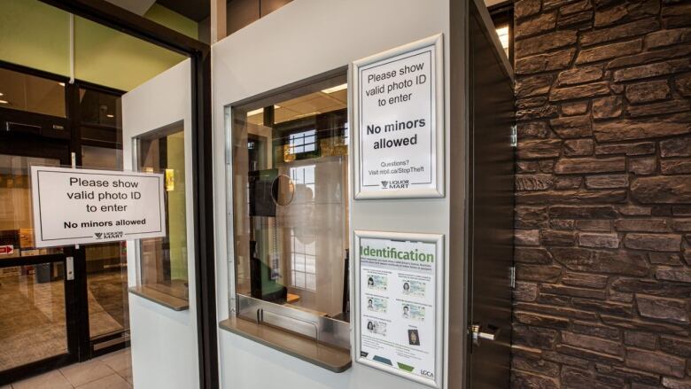 Image of secure entrance at Liquor Mart, including signs asking for photo ID.