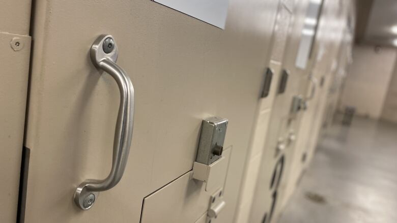 a brown metal door and hallway of a jail