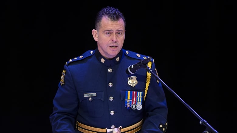 A White man is seen at a podium wearing high decorated police wear