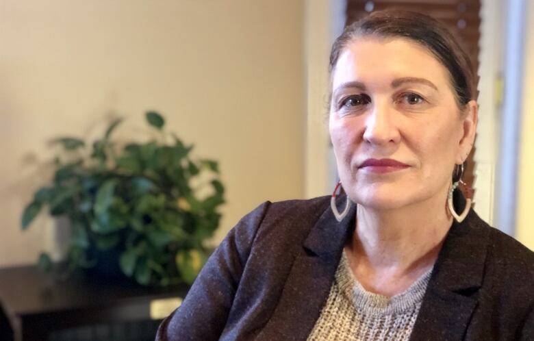 Tammy Roberts sits in an office, unsmiling, wearing earrings.