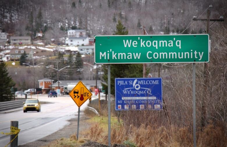 Image looking down the highway with a sign in the foreground saying, 'We'koqma'q Mi'kmaw Community.'