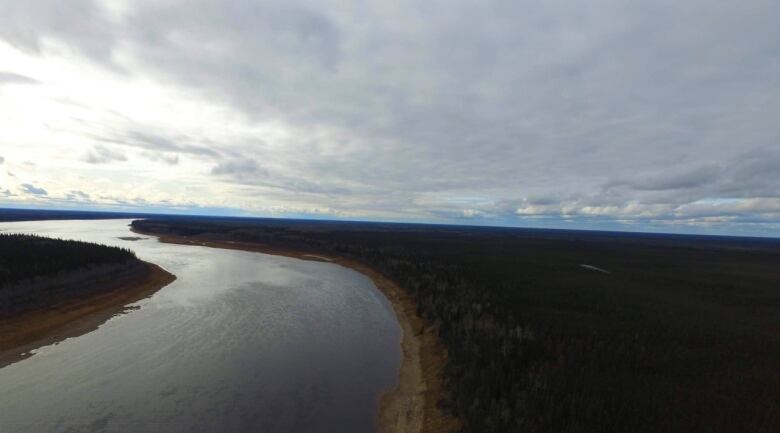 A wide river bends to the left, surrounded by wilderness and an overcast sky. 