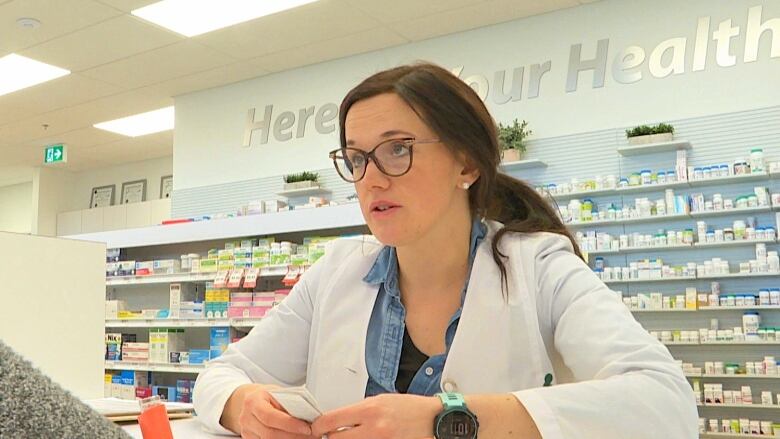 A pharmacist stands at a pharmacy desk