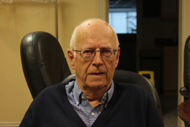 A man wearing glasses sits for a photo.