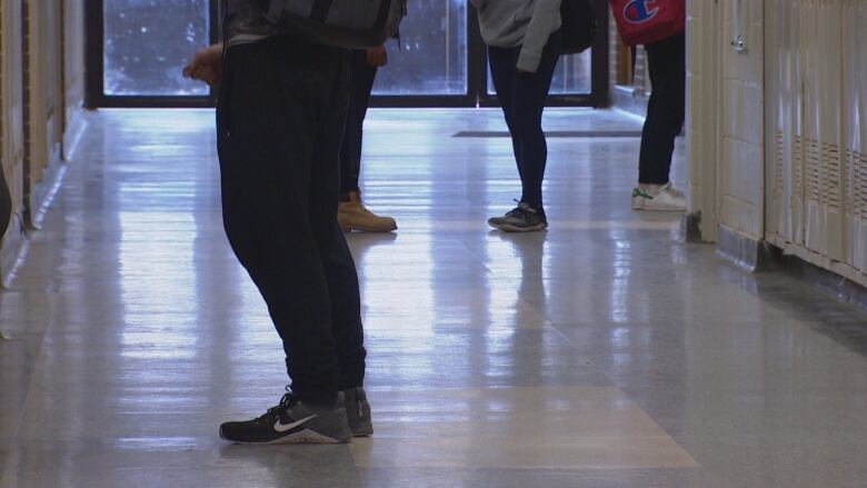 Students are seen in the hallway of a school.