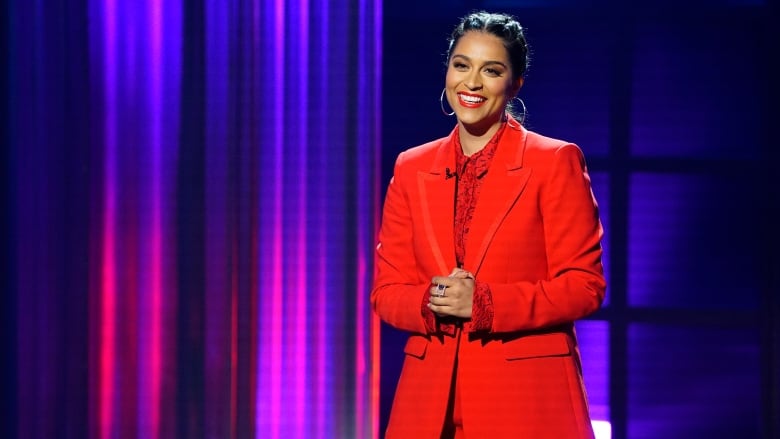 Lily Singh on stage wearing a red suit